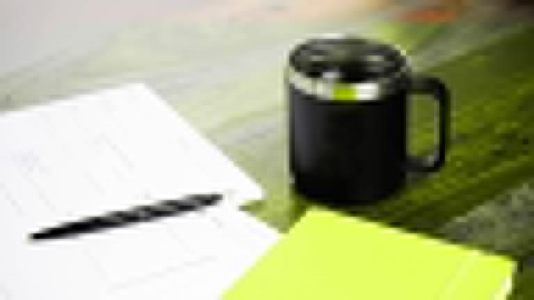 Coffee cup and pen with papers and notepads