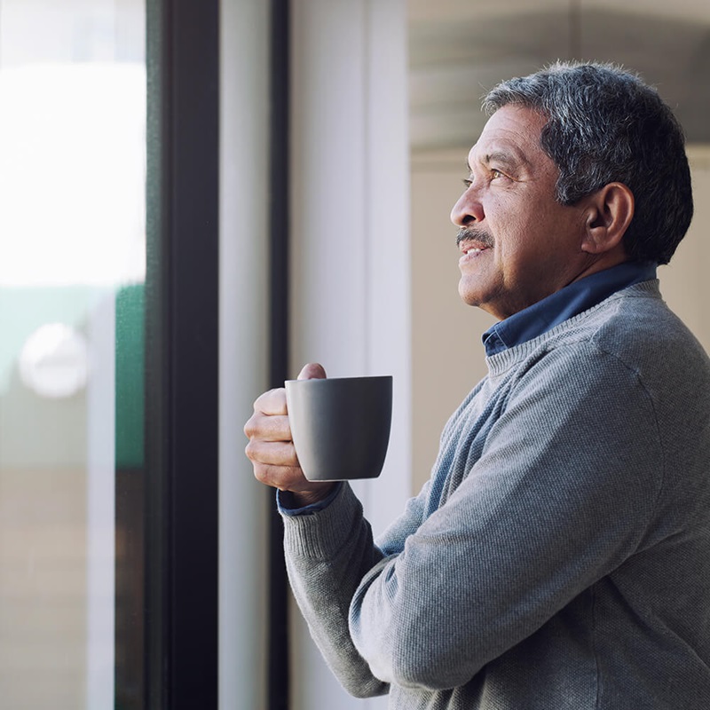 Man looking out window thinking