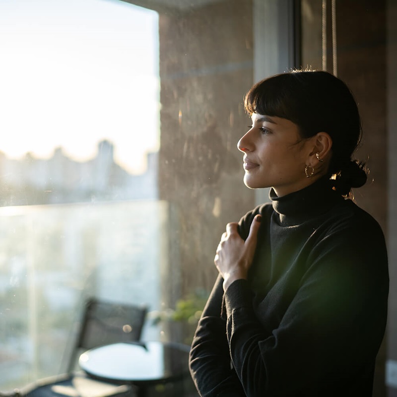 Woman gazing out window thinking