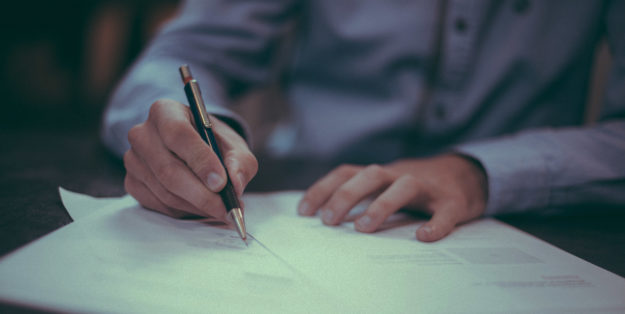 Close up image of someone writing with a pen on paper