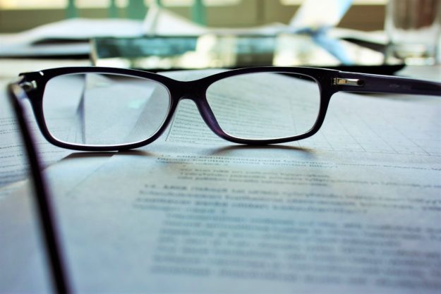 A close-up picture of a pair of reading glasses on top of a contract